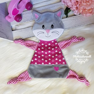 May include: A gray and pink cat-shaped baby toy with a pink heart pattern on the front and pink and white striped arms and legs. The toy has a knotted end on each arm and leg.