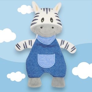 May include: A plush zebra toy with a white body, black stripes, and a gray face. It wears blue denim overalls with a pocket. The toy has a friendly expression and is set against a light blue background with white clouds.