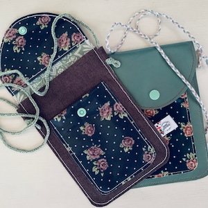 Könnte beinhalten: Zwei kleine Umhängetaschen mit Blumenstoff und eine grüne Ledertasche. Die Taschen haben einen Klappverschluss und ein kleines Fach auf der Vorderseite. Die Taschen haben einen grünen Knopfverschluss und einen grünen Trageriemen.