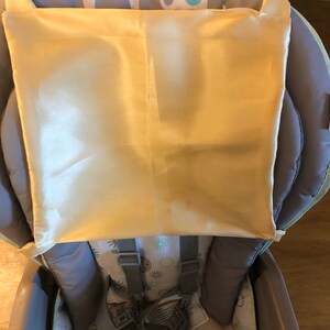 May include: A gray high chair with a yellow satin bib and a patterned seat. The chair has a five-point harness and a removable tray.