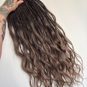 May include: Brown and light brown dreadlocks with wavy ends. The dreadlocks are a mix of dark and light brown shades, creating a natural, textured look. The hair is styled to appear long and flowing, suitable for various hairstyles.