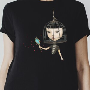 K&ouml;nnte beinhalten: Ein schwarzes T-Shirt mit einem Motiv einer Person mit einem K&auml;fig &uuml;ber dem Kopf, die einen Spiegel h&auml;lt. Die Person tr&auml;gt ein gestreiftes Hemd und hat rote Herzen um sich herum schweben.