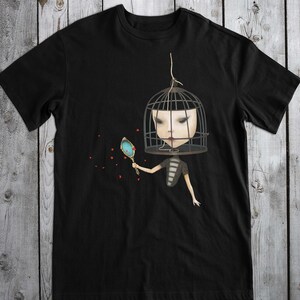 K&ouml;nnte beinhalten: Schwarzes T-Shirt mit einem Motiv einer Person, deren Kopf in einem Vogelk&auml;fig steckt und einen Spiegel h&auml;lt. Rote Herzen sind um die Person herum verstreut.