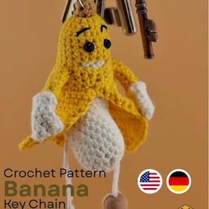 Könnte beinhalten: Ein handgefertigter gehäkelter Bananen-Schlüsselanhänger mit einem lächelnden Gesicht, gelber Schale und weißem Körper. Der Schlüsselanhänger hat kleine Holzperlen und ist an einem Metall-Schlüsselring mit Schlüsseln befestigt. Der Text "Crochet Pattern Banana Key Chain" ist sichtbar.