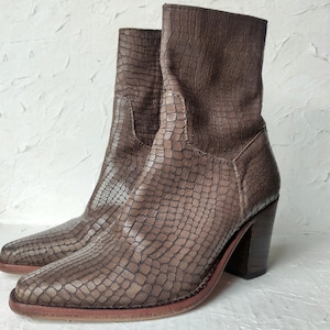 May include: A pair of brown leather ankle boots with a snakeskin pattern and a block heel.