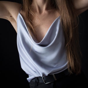 May include: A light blue satin top with a cowl neck and a black belt.