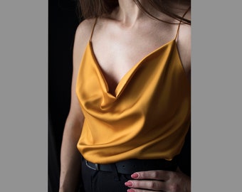 May include: A mustard yellow satin top with a cowl neck and thin straps.