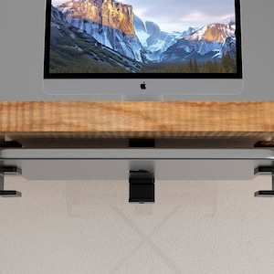 May include: A black metal laptop stand with two arms that attach to the underside of a desk. The stand is designed to hold a laptop or tablet.