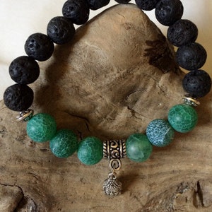 以下が含まれることがあります： 黒い溶岩と緑の瑪瑙のビーズで作られたブレスレット。シルバーの仏陀のチャームが付いています。