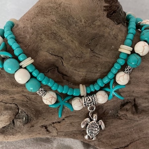 May include: A turquoise and white beaded bracelet with a silver turtle charm and starfish accents.