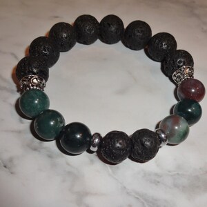 May include: A black lava rock bracelet with green and red agate beads and silver accents.