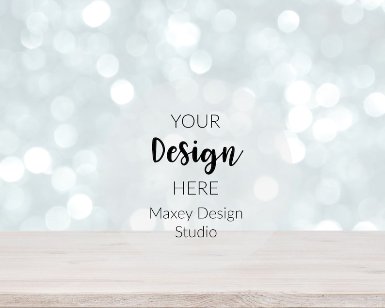 May include: A white wooden table top with a blurred background of silver and white bokeh lights. The text "YOUR Design HERE Maxey Design Studio" is printed on the background.