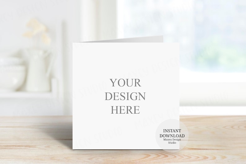 May include: A square white greeting card mockup featuring the centered gray text YOUR DESIGN HERE. A circular badge in the bottom right corner contains the text INSTANT DOWNLOAD Maxey Design Studio. The card is displayed in a clean, neutral setting.