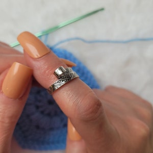 Worked silver-colored crochet or knitting ring, a yarn tension aid for crocheting and knitting.