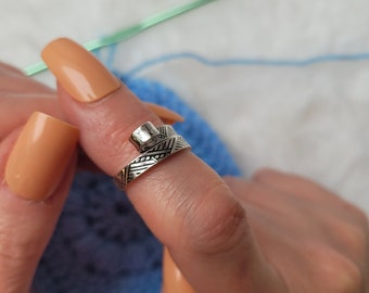 Worked silver-colored crochet or knitting ring, a yarn tension aid for crocheting and knitting.