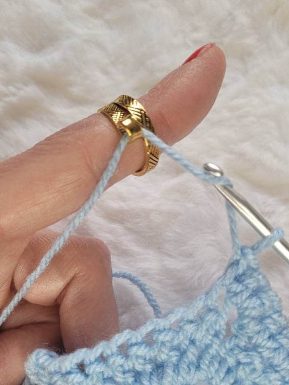 Worked gold-colored crochet or knitting ring, a yarn tension aid for  crocheting and knitting.
