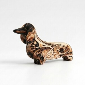 May include: A dachshund figurine featuring a marbled pattern of swirling dark brown, tan, and cream colors. The sculpture depicts the dog in a standing position with its head turned slightly to the side, showcasing a smooth, glossy finish.