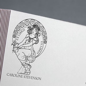 Puede incluir: Ilustraci&oacute;n en blanco y negro de una mujer sosteniendo una flor, con el texto "Ex Libris" a cada lado de ella. El texto "Caroline Stevenson" est&aacute; debajo de la ilustraci&oacute;n.