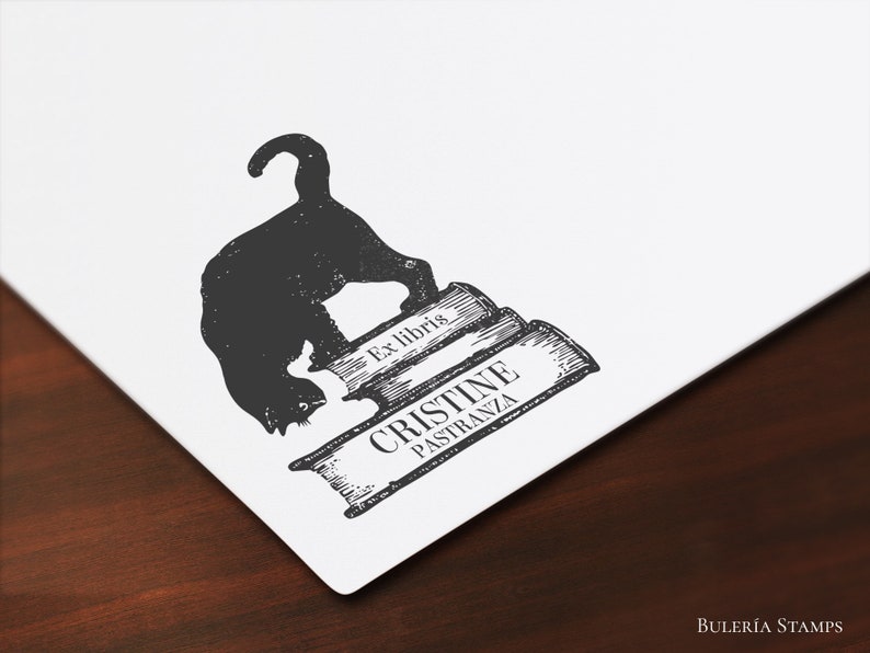 K&ouml;nnte beinhalten: Schwarz-wei&szlig;-Illustration einer Katze, die auf einem Stapel B&uuml;cher sitzt. Der Text "Ex libris" und "CRISTINE PASTRANZA" ist auf den B&uuml;chern gedruckt.