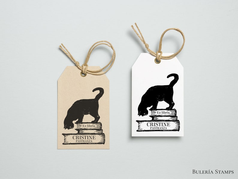 K&ouml;nnte beinhalten: Zwei braune und wei&szlig;e Geschenkanh&auml;nger mit einer schwarzen Silhouette einer Katze, die einen Stapel B&uuml;cher liest. Der Text auf den Anh&auml;ngern lautet "Ex libris Cristine Pastranza".