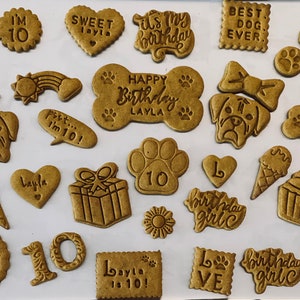 May include: A collection of dog birthday treat cookies with various designs and messages, including "Happy Birthday Layla", "Best Dog Ever", "Woof U", "It's My Birthday", "Sweet Layla", "I'm 10", "Birthday Girl", "Layla is 10!" and "10".