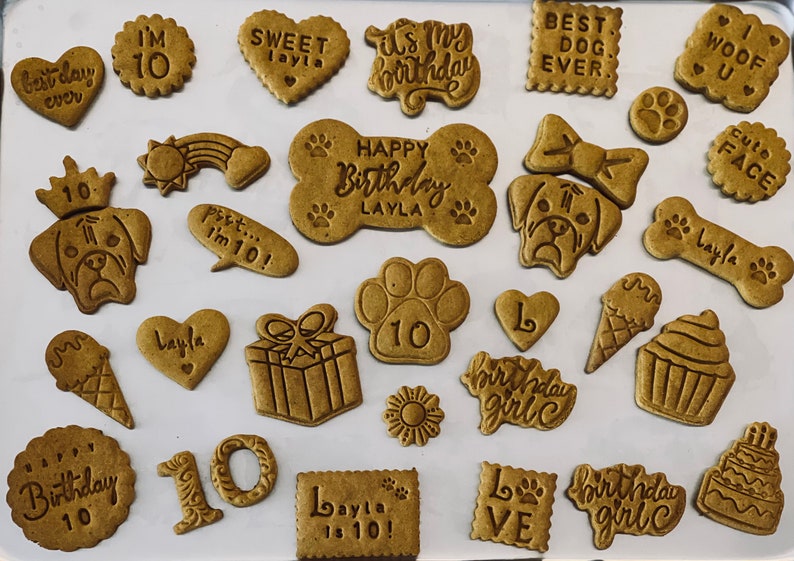 May include: A collection of dog birthday treat cookies with various designs and messages, including "Happy Birthday Layla", "Best Dog Ever", "Woof U", "It's My Birthday", "Sweet Layla", "I'm 10", "Birthday Girl", "Layla is 10!" and "10".