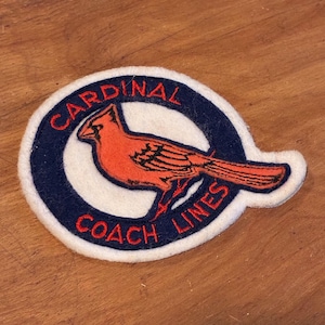 May include: A vintage patch featuring a red cardinal bird design. The patch has a white background with a navy blue border. The words "CARDINAL COACH LINES" are in red lettering, encircling the bird.