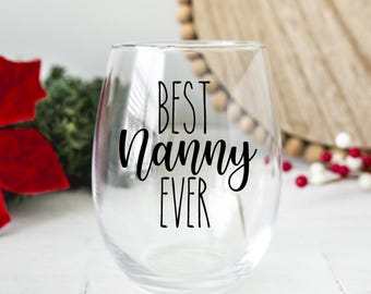 May include: A clear stemless wine glass featuring the black printed text BEST Nanny EVER. The glass has a rounded bowl shape and a smooth rim, designed for holding beverages. The lettering is displayed in a combination of block and script fonts.