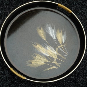 May include: A black serving tray with a gold rim and a design of wheat stalks in gold and silver.
