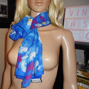 May include: A white ceramic mug with a black handle and the text "But First, Coffee" in a black, handwritten-style font. The mug is on a white surface.