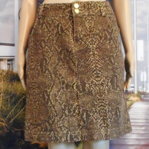 May include: A brown and gold snakeskin print skirt with a gold button closure.