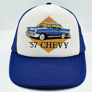 Puede incluir: Una gorra de camionero azul y blanca con un gráfico de coche Chevrolet azul de 1957 y el texto '57 CHEVY' en la parte delantera. La gorra tiene una parte trasera de malla azul.