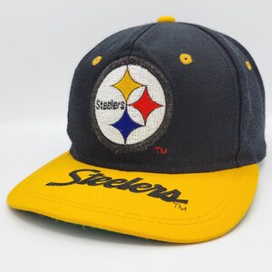 May include: Black and yellow baseball cap with the Pittsburgh Steelers logo and the word "Steelers" in a script font on the front.