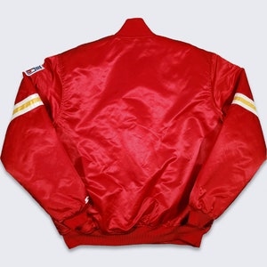 May include: A red satin bomber jacket with white and gold striped sleeves. The jacket has a zipper closure and a ribbed collar, cuffs, and waistband.