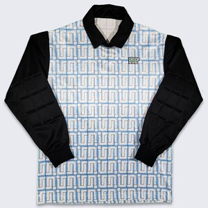 May include: A white and blue long-sleeved soccer jersey with black padded sleeves. The jersey has a geometric pattern and the text "MR" on the right side of the chest.