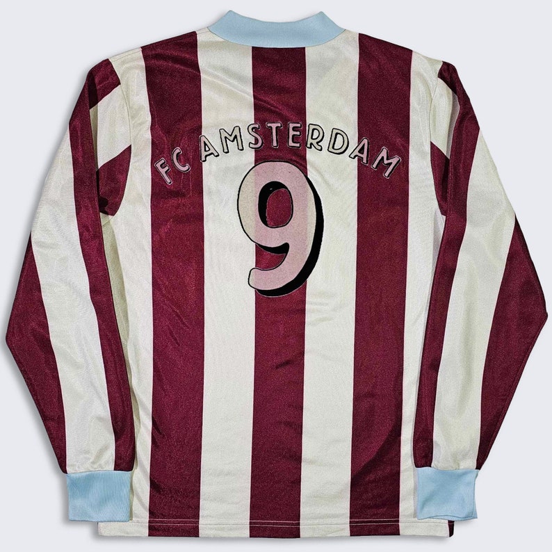 Puede incluir: Una camiseta de f&uacute;tbol de manga larga a rayas blancas y marrones con el texto "FC AMSTERDAM" y el n&uacute;mero "9" en la espalda.