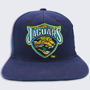 May include: A navy blue baseball cap with a yellow, blue, and white Jacksonville Jaguars logo. The logo features a jaguar's head with the team name "Jaguars" above it.