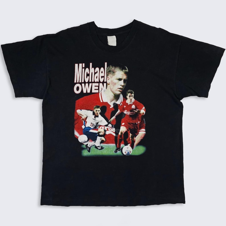 May include: Black t-shirt with a graphic print of Michael Owen, a famous soccer player, in a red and white soccer uniform. The text "Michael Owen" is printed in white on the shirt.