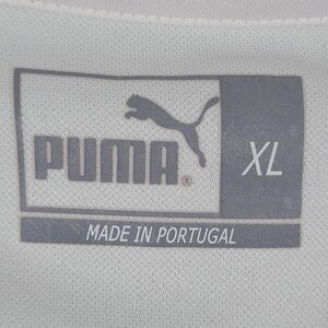 K&ouml;nnte beinhalten: Ein graues Puma-Logo mit dem Wort "Puma" und einem eingetragenen Warenzeichen. Die Gr&ouml;&szlig;e "XL" ist unter dem Logo gedruckt. Der Text "Made in Portugal" ist unter der Gr&ouml;&szlig;e gedruckt.