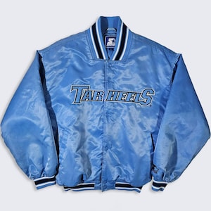 May include: Light blue satin jacket with the text "Tar Heels" across the chest. The jacket has a button-up front, a ribbed collar, cuffs, and hem with black and white stripes. The Starter logo is visible on the collar.