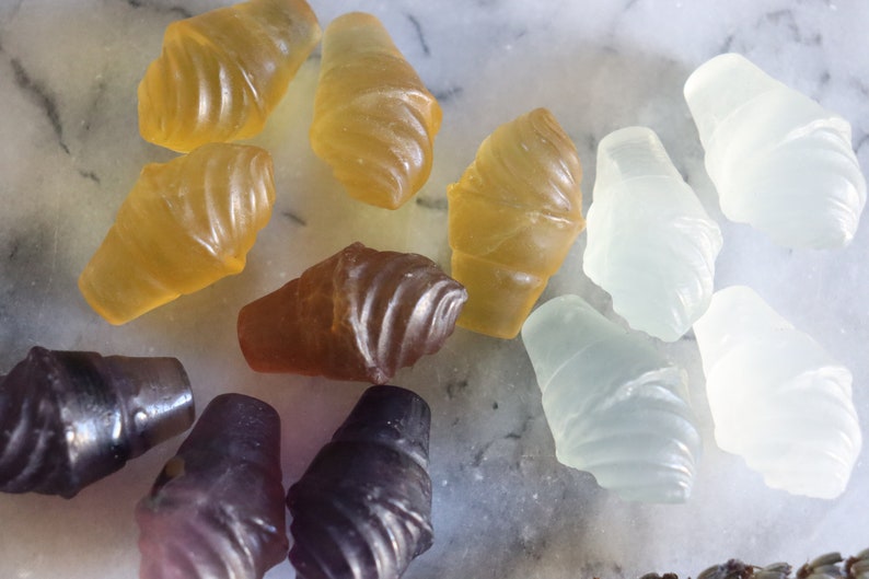 May include: Assortment of colorful gummy candies shaped like ice cream cones. The candies are in shades of yellow, brown, purple, and white.