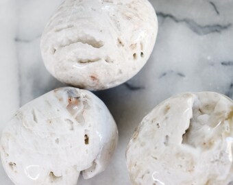 May include: Three white agate stones with a rough, textured surface. The stones are smooth and polished, with a natural, organic look.