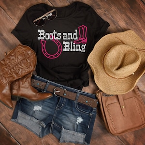 Puede incluir: Una camiseta negra con el texto "Boots and Bling" en pedrer&iacute;a rosa. La camiseta presenta una herradura y un gr&aacute;fico de bota. La camiseta se combina con pantalones cortos de mezclilla, botas vaqueras marrones, una bolsa de cuero marr&oacute;n y un sombrero de vaquero de paja.