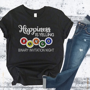 May include: Black t-shirt with the text "Happiness is yelling BINGO" in white rhinestones. The word BINGO is spelled out with colorful bingo balls. The text "Binary Invitation Night" is below the design.
