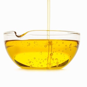 Puede incluir: Un bol de vidrio transparente lleno de líquido amarillo, con más líquido que se vierte en el bol desde arriba.