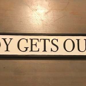 May include: Black and white sign with the text "NOBODY GETS OUT SOBER" on a white background.