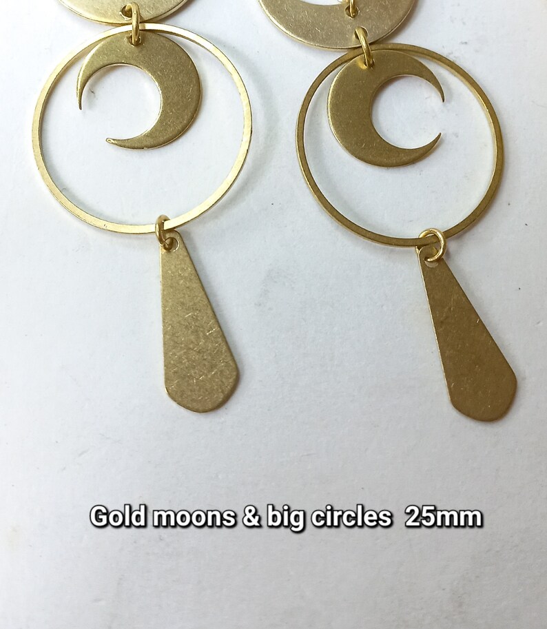 Op de afbeelding: Goudkleurige oorbellen met maan- en cirkelontwerpen, met een druppelvormige hanger. De oorbellen zijn ongeveer 25 mm groot. De tekst "Gold moons & big circles" is zichtbaar in de afbeelding.