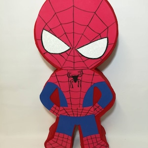 May include: A red and blue foam cutout of Spiderman with a black spider web design. The figure has a large head with white eyes and a black spider on the chest.