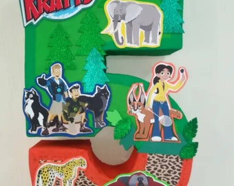 May include: A green cardboard number five decorated with Wild Kratts characters and animals. The number is decorated with green trees, a cheetah, an elephant, a gorilla, and a cat. The number is decorated with a leopard print pattern.