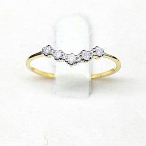 Op de afbeelding: Een delicate gouden ring met een gebogen rij kleine, glinsterende diamanten.